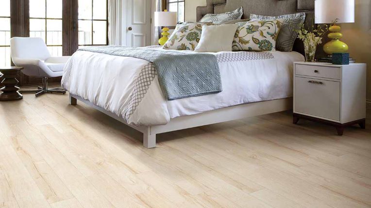 warm toned wood look laminate flooring with long planks in a stunning bedroom